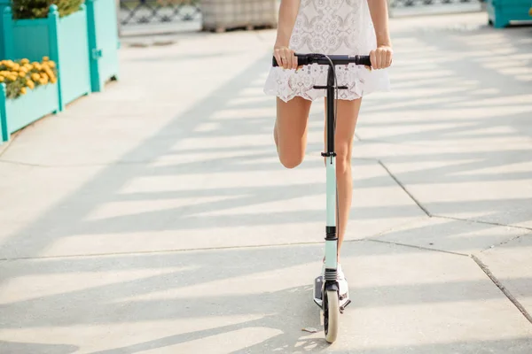 Primer plano de niña pierna corriendo en patada azul scooter a lo largo de la calle —  Fotos de Stock