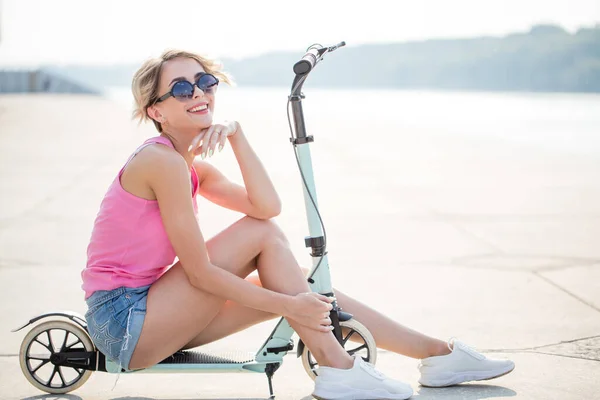 Positiv blond kvinna sitter på blå sparkcykel — Stockfoto