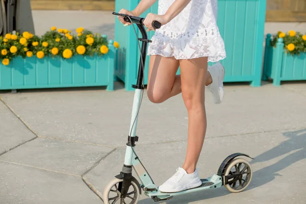 Fechar a perna da menina correndo em azul chute scooter ao longo da rua — Fotografia de Stock