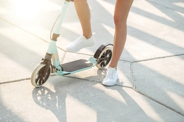 Close-up vrouw benen op blauwe kick scooter op weg in de zomer dag — Stockfoto