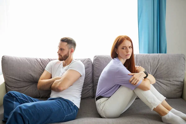 Couple lost in sad thoughts sitting together on sofa thinking feels troubled about problems — Stock Photo, Image