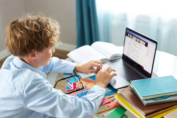 컴퓨터 앞에 앉아서 인터넷으로 공부하는 코카서스 소년 — 스톡 사진