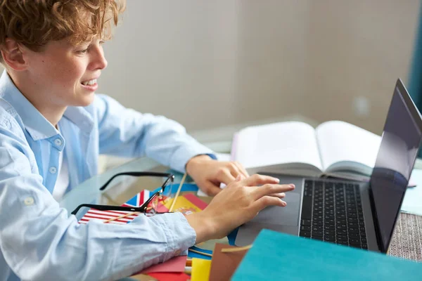 Skolpojke skriver rapport på laptop, gör läxor — Stockfoto