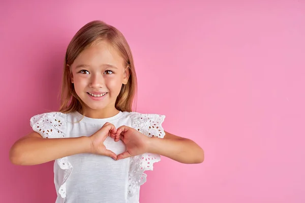 Barátságos kedves lány mutatja szív készült kéz a kamera — Stock Fotó