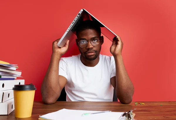 Sério afro-americano homem segurar laptop sobre sua cabeça, cansado para trabalhar — Fotografia de Stock