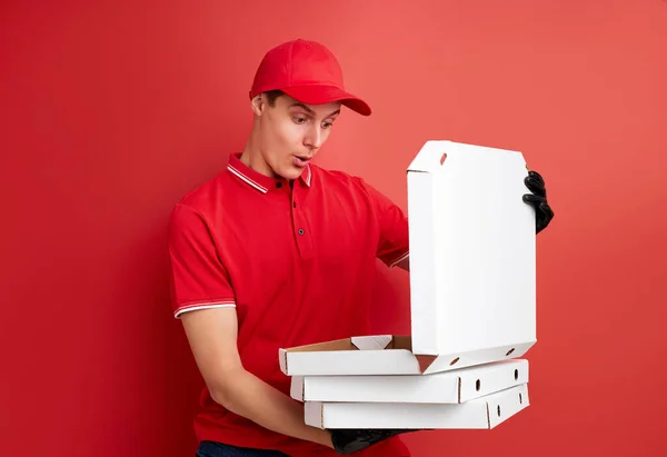 Chocado mensajero mira con sorpresa a la pizza en las manos —  Fotos de Stock