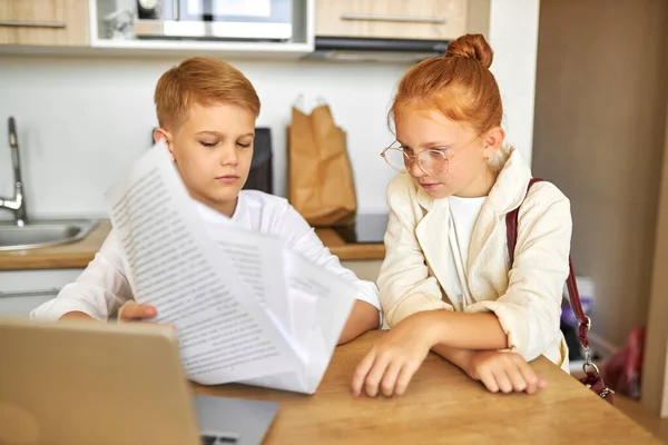 Кавказские дети вошли в роль взрослых, работают на ноутбуке с документами — стоковое фото