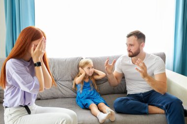 üzgün, çaresiz küçük kız ebeveynler tartışırken, kulakları tıkıyor