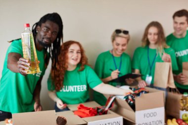 Şefkatli Afrikalı gönüllü adam fakir adamlara ayçiçeği yağı veriyor.