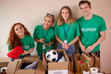 Mutlu genç gönüllüler hayır kurumları için giysi ve yiyecek bağışlıyorlar.