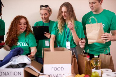 Mutlu genç gönüllüler hayır kurumları için giysi ve yiyecek bağışlıyorlar.