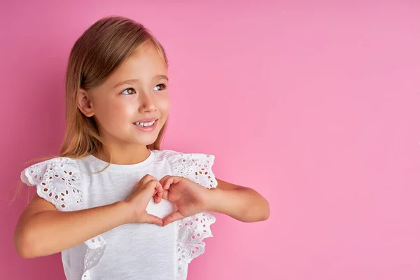 친절 한 어린 소녀는 카메라를 통해 손으로 심장을 만들었음을 보여준다 — 스톡 사진