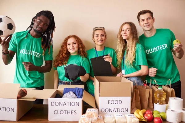 diverse volunteers packing, collecting humanitarian aid in donation box