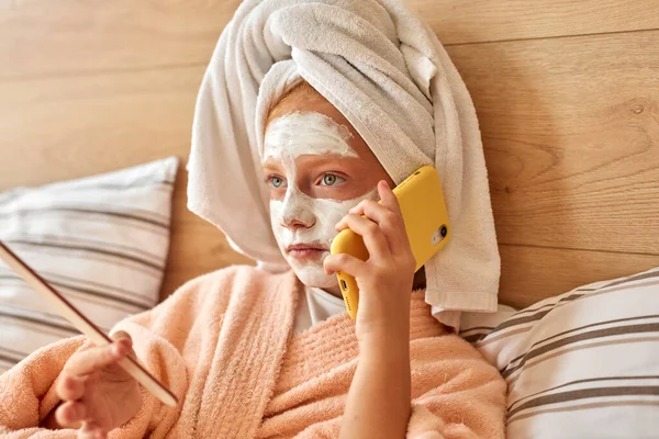 Atraktivní dítě dívka mluvit na telefonu ležící na posteli — Stock fotografie