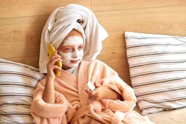 Attractive kid girl talk on phone lying on bed — Stock Photo, Image