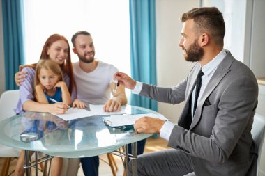 Genç beyaz bir aile, emlakçı tarafından evlerinden anahtarlarını alıyor.