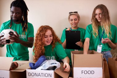 Çeşitli gönüllüler depoda yiyecek ve giyecek bağışları topluyor.