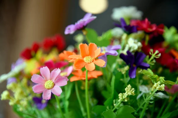 Many fake flowers are in the same bouquet. Color full of fabric flowers.