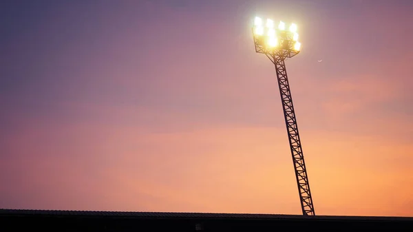 The Stadium Spot-light tower over football field at night time.