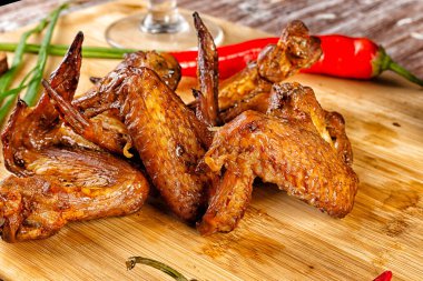 Masanın üzerinde tütsülenmiş tavuk kanadı olan kompozisyon