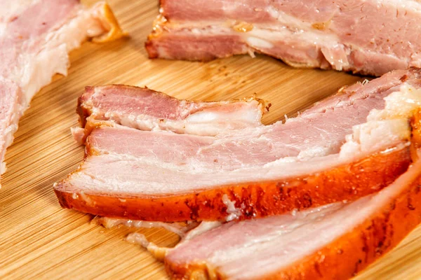 Carne ahumada cortada en rodajas se encuentra en una mesa de madera — Foto de Stock