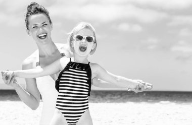 Aile eğlence beyaz kum üzerinde. Modern anne ve kızı eğleniyor sahil üzerinde mayo içinde gülümseyen zaman