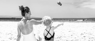 Aile eğlence beyaz kum üzerinde. Modern anne ve çocuk beachwear sahilde bir şeye işaret içinde arkasından gördüm