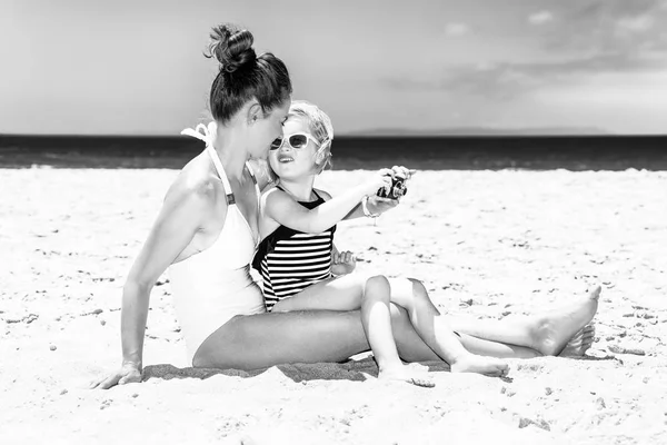 白い砂の上の家族の楽しみです デジタル カメラ撮影で海岸にビーチウェアで若い母と娘 — ストック写真