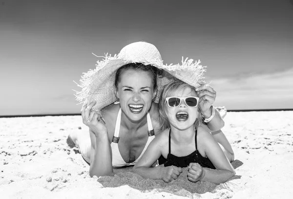 Aile eğlence beyaz kum üzerinde. Modern anne ve çocuk mayo sahil üzerinde döşeme içinde gülümseyen portresi