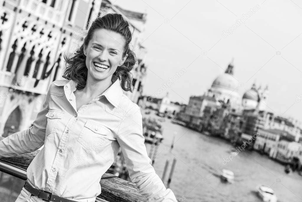 Smiling young woman standing on bridge with grand canal view in venice, italy
