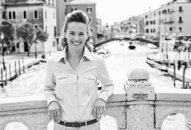 Zarif bir esmer turist rahat bir köprü karşı Venedik'in kanallarının, birinin üzerine gülümseyen eğilir. O rahat ve mutlu..