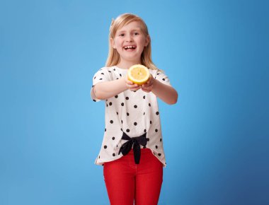 kırmızı pantolon bir limon yarısı mavi arka plan veren modern çocuk gülümseyen