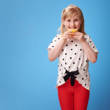 modern kız kırmızı pantolon yarısı mavi zemin üzerine bir limon suyu içme gülümseyen