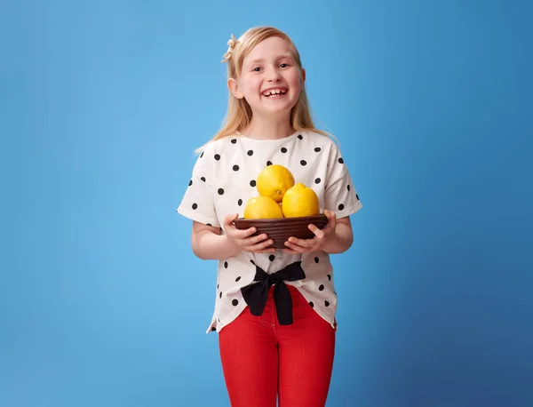 Усміхнена Сучасна Дівчина Червоних Штанях Показує Тарілку Лимонами Синьому Фоні — стокове фото