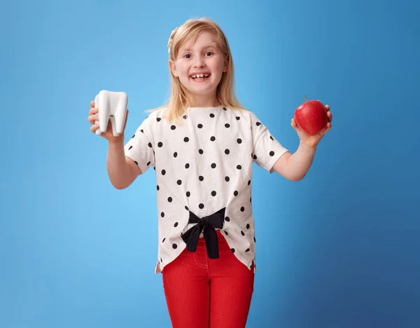 歯とリンゴを示す赤いパンツで幸せなモダン ガール — ストック写真