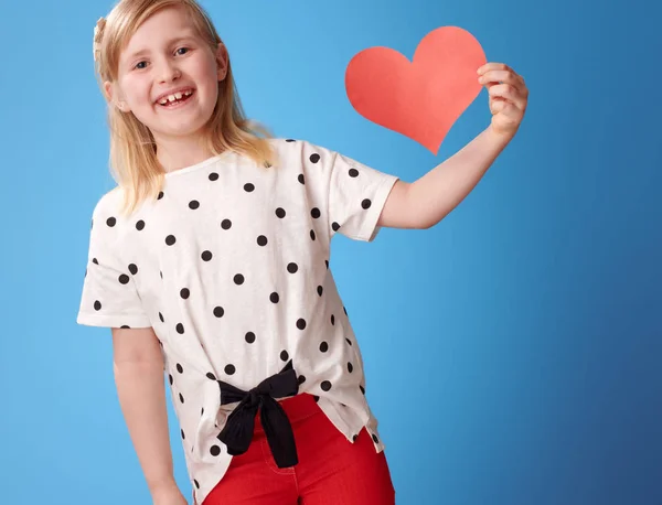Улыбающийся Современный Ребенок Красных Штанах Показывает Бумажное Сердце Синем Фоне — стоковое фото