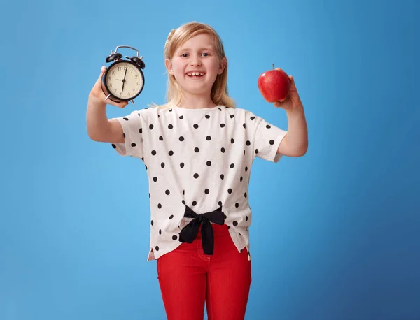 Ler Moderna Barn Röda Byxor Visar Väckarklocka Och Ett Äpple — Stockfoto
