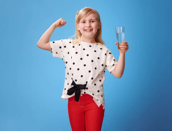 Smilende Moderne Pige Røde Bukser Med Glas Vand Viser Biceps - Stock-foto