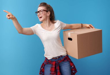 mavi arka plan karşı bir şey gösteren bir karton kutu ile beyaz gömlekli mutlu modern kadın