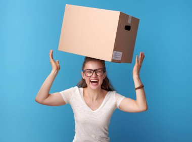 Üzerinde mavi arka plan izole kafasına bir karton kutu ile beyaz gömlekli mutlu etkin hipster portresi