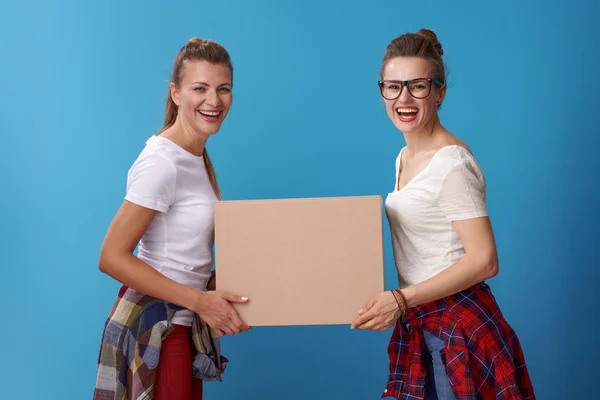 青い背景に段ボール箱を一緒に保持する白いシャツで幸せな近代的な流行に敏感な友人の肖像画 — ストック写真