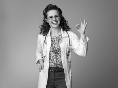 gülümseyen iyi jest gösterilen beyaz tıbbi elbise içinde çocuk doktoru kadın