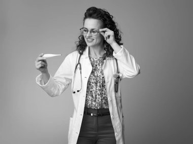 Termometre seyir beyaz tıbbi elbise içinde gülümseyen çocuk doktoru Doktor