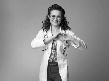 kalp gösterilen beyaz tıbbi elbise içinde gülümseyen çocuk doktoru Doktor eller şeklinde