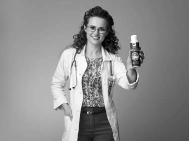 Çocuk doktoru böcek kovucu gösterilen beyaz tıbbi elbise içinde gülümseyen