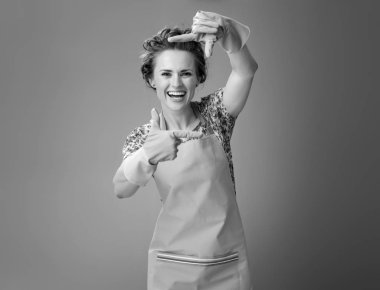 Lastik eldivenli elleriyle çerçeveleme modern ev kadını gülümseyen 