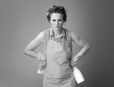 Gergin genç kadın temizlik sünger ve deterjan ile bir önlük