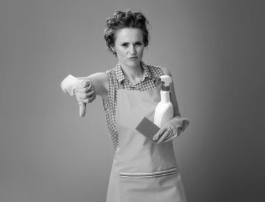 Lastik eldiven ve mutfak sünger ve deterjan başparmak aşağı gösterilen bir şişe ile modern ev kadını 