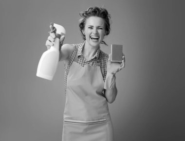 gülümseyen genç kadın lastik eldiven ve bir şişe deterjan gösterilen mutfak sünger ile 