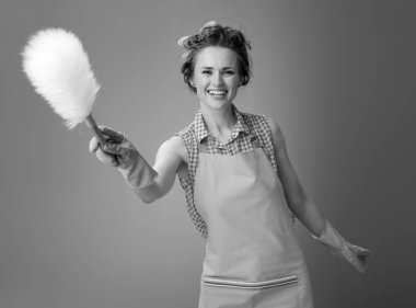 gülümseyen genç kadın bir toz bezi fırça kullanarak bir önlük